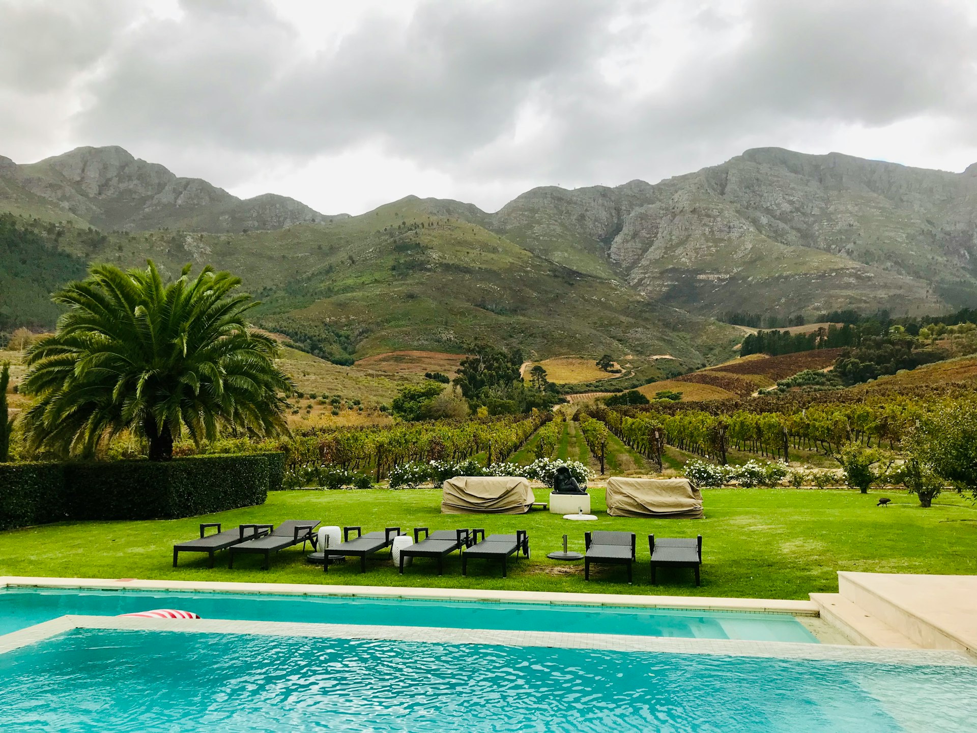 A swimming pool with lounge chairs and mountains in the background